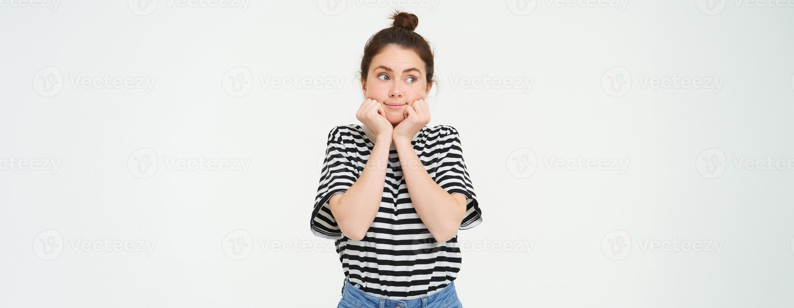 Wellbeing and women concept. Portrait of young woman with cute face, holds hands near head and smiles, isolated against white background photo