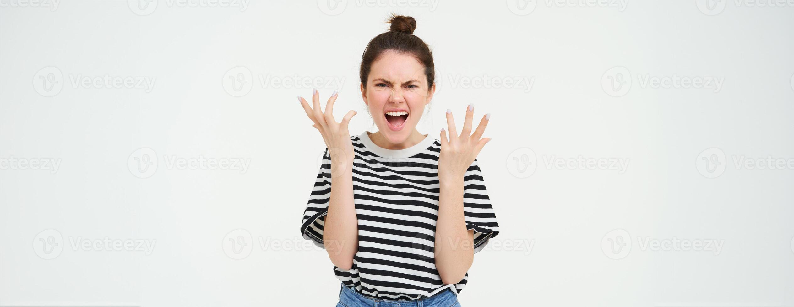 Image of angry woman shouts and shakes hands, stands in casual clothes over white background photo