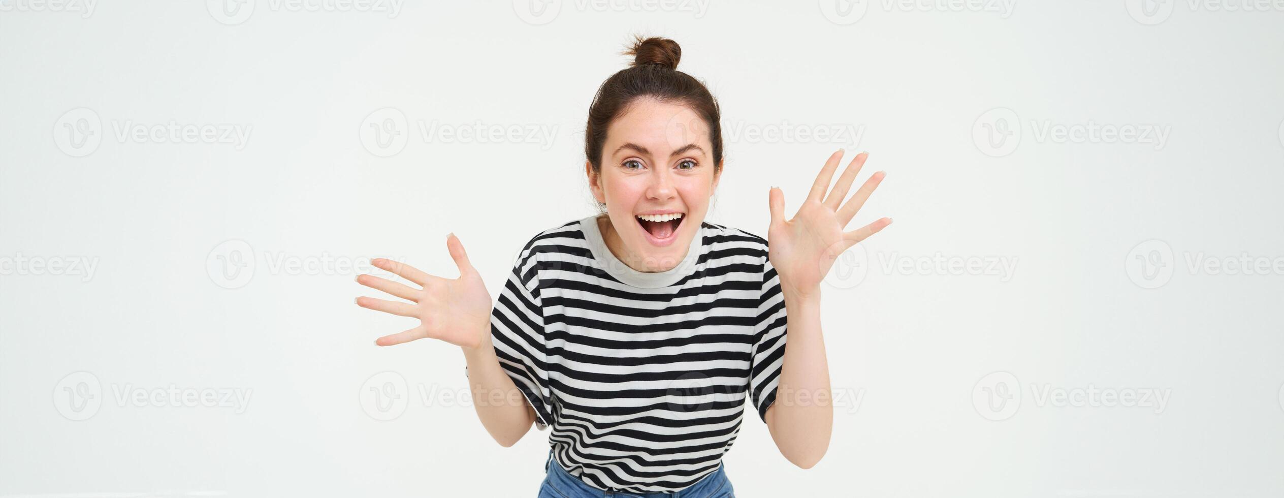 Portrait of happy, beautiful girl makes jazz hands, tells big news, revelation, introduces surprise, stands over white background photo