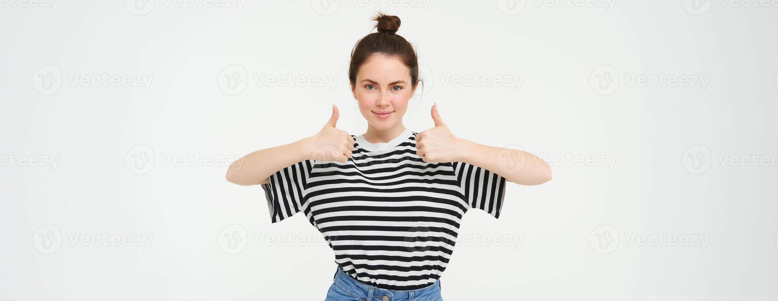 Portrait of confident, beautiful woman, showing thumbs up, recommends product, likes and approves, stands over white background photo