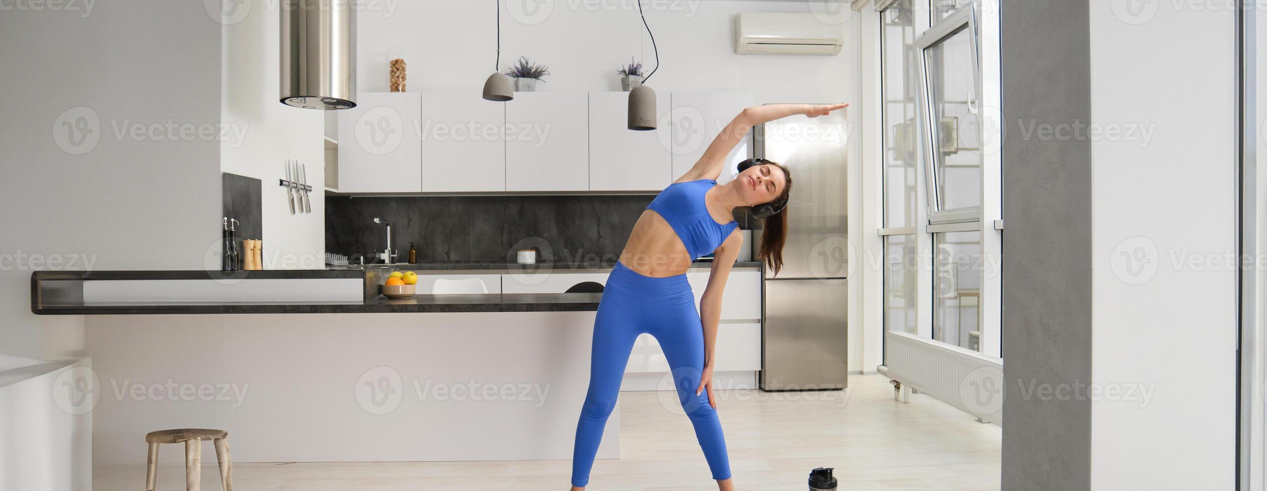 retrato de joven mujer haciendo aeróbicos ejercicios en vivo habitación, deporte formación a hogar, en pie en caucho aptitud estera y haciendo rutina de ejercicio foto