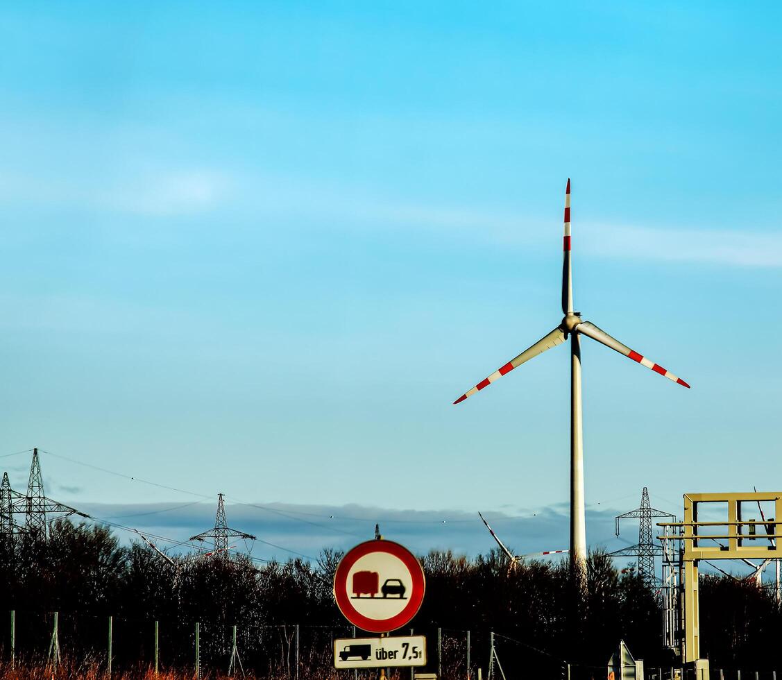 viento granja parque y alto voltaje torres siguiente a un la carretera en Austria en soleado clima. foto