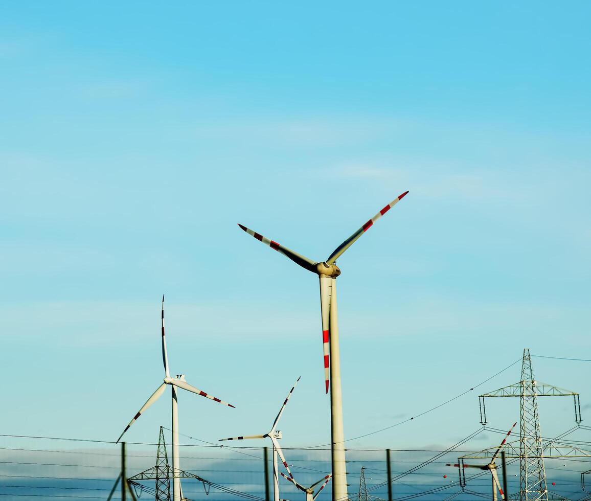 Wind farm park and high voltage towers next to a road in Austria in sunny weather. photo