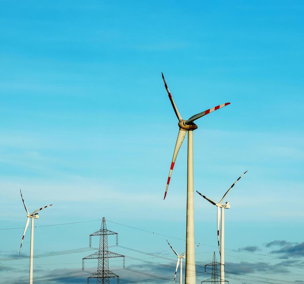 viento granja parque y alto voltaje torres siguiente a un la carretera en Austria en soleado clima. foto