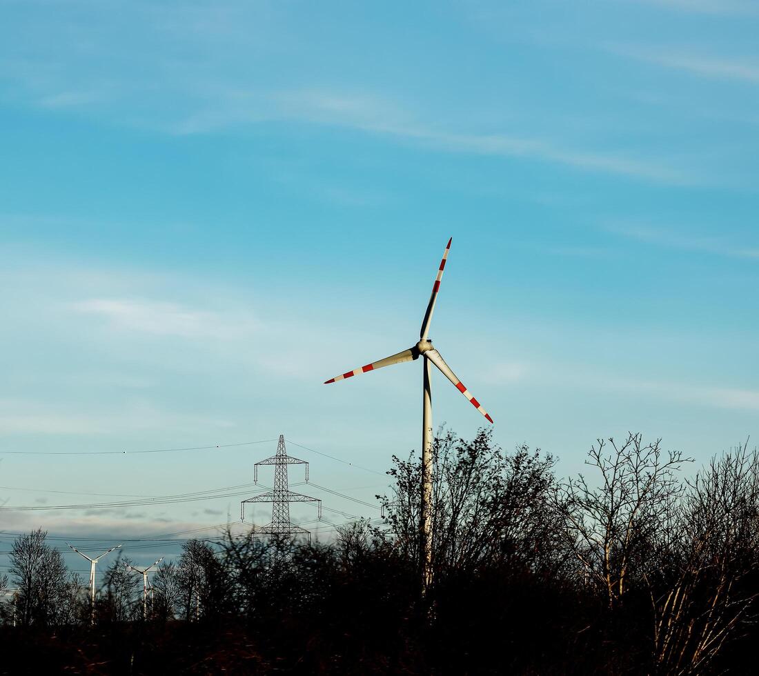 viento granja parque y alto voltaje torres siguiente a un la carretera en Austria en soleado clima. foto