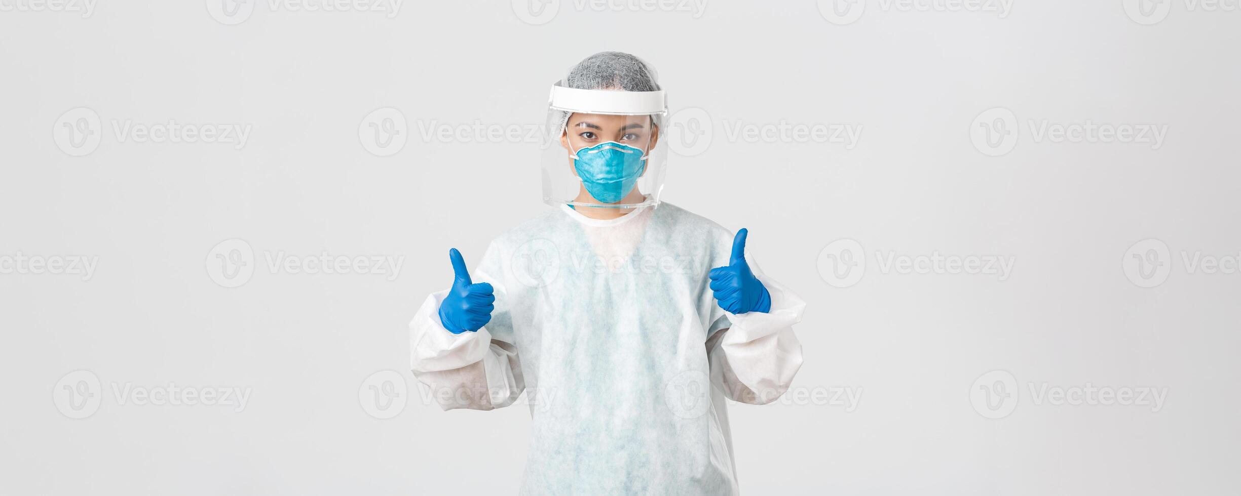 Covid-19, coronavirus disease, healthcare workers concept. Confident serious-looking asian female doctor working in contagious zones in personal protective equipment, show thumbs-up photo