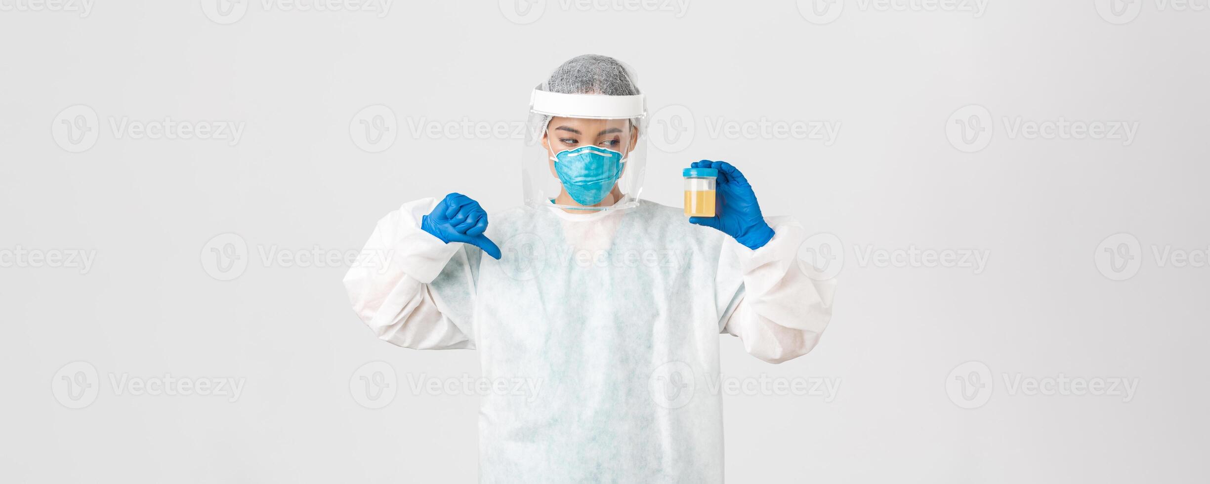 Covid-19, coronavirus disease, healthcare workers concept. Side view of serious tech lab employee, researcher in personal protective equipment show thumb-down in disapproval, bad analyze result photo