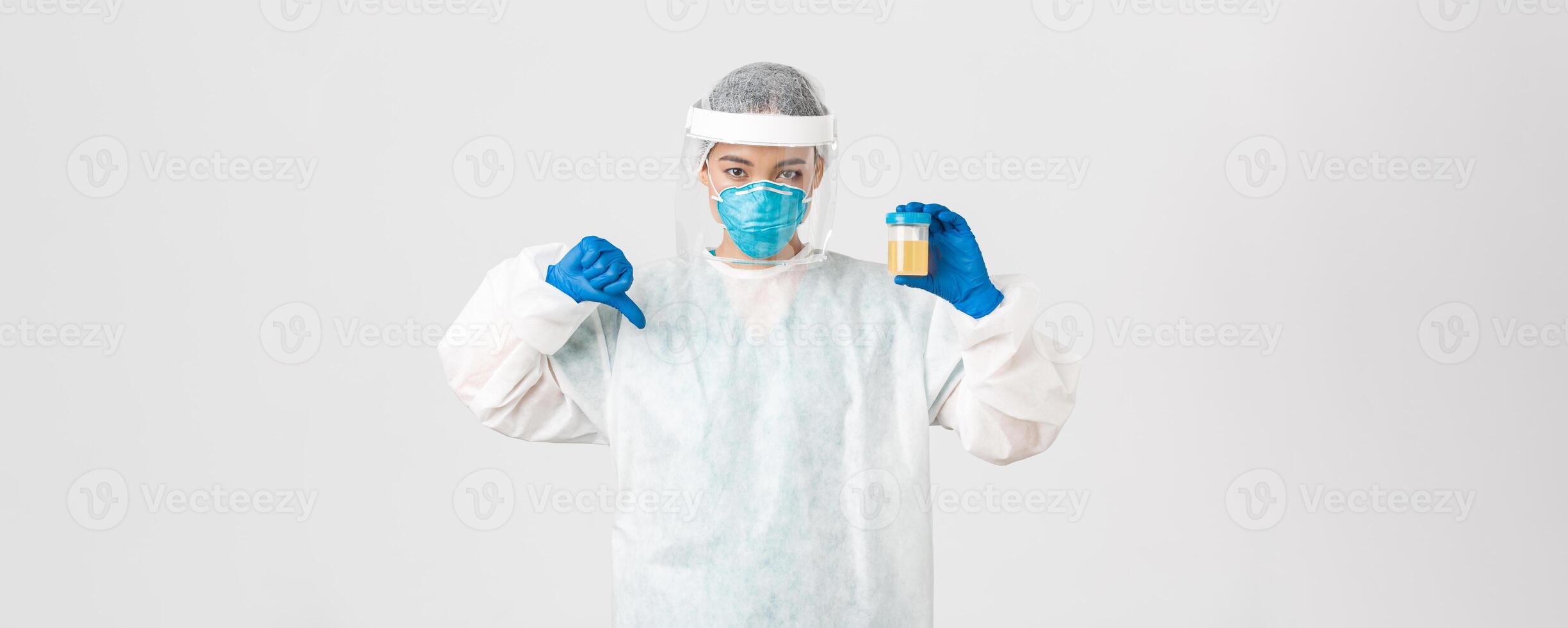 Covid-19, coronavirus disease, healthcare workers concept. Side view of serious tech lab employee, researcher in personal protective equipment show thumb-down in disapproval, bad analyze result photo
