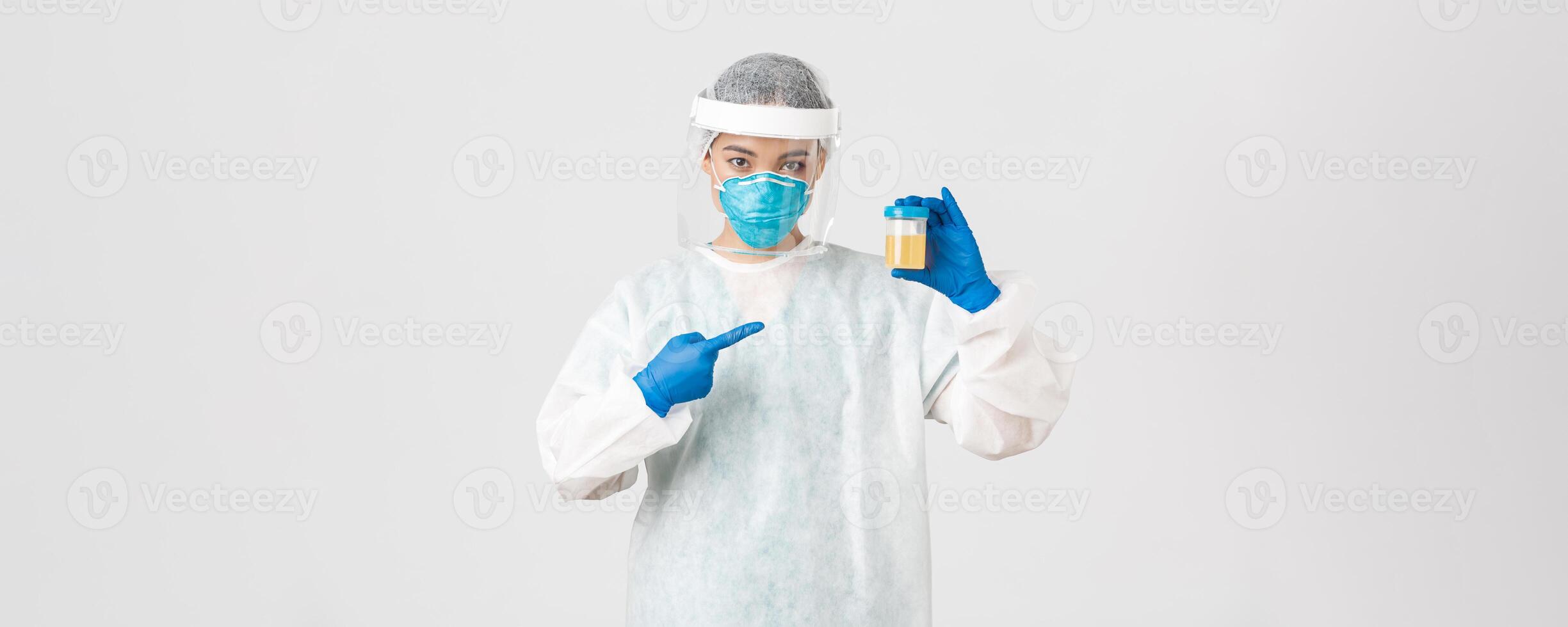 Covid-19, coronavirus disease, healthcare workers concept. Side view of serious-looking tech lab employee, researcher in personal protective equipment, pointing at urine analyze photo