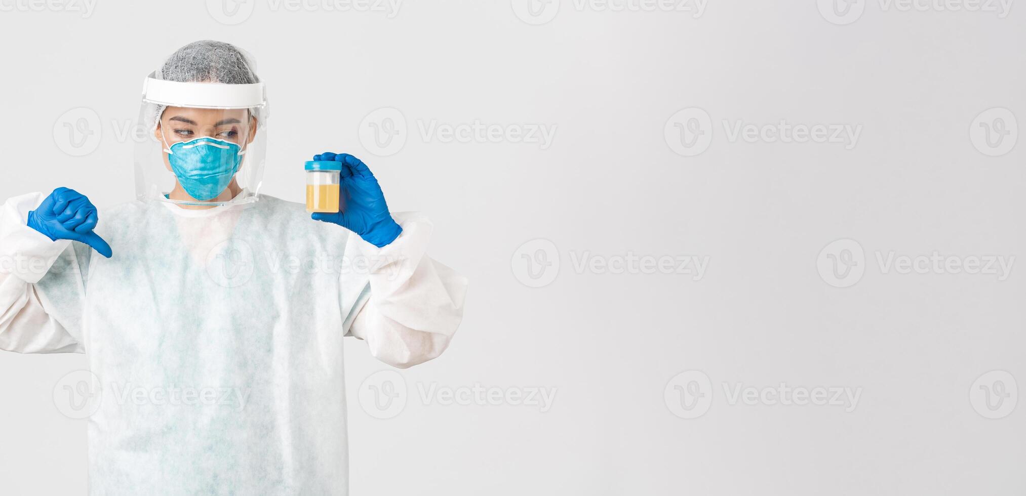 Covid-19, coronavirus disease, healthcare workers concept. Side view of serious tech lab employee, researcher in personal protective equipment show thumb-down in disapproval, bad analyze result photo