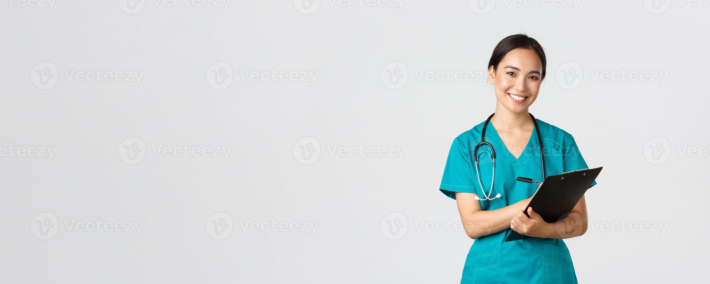 Healthcare workers, preventing virus, quarantine campaign concept. Cheerful friendly asian female physician, doctor with clipboard during daily checkup, standing white background photo