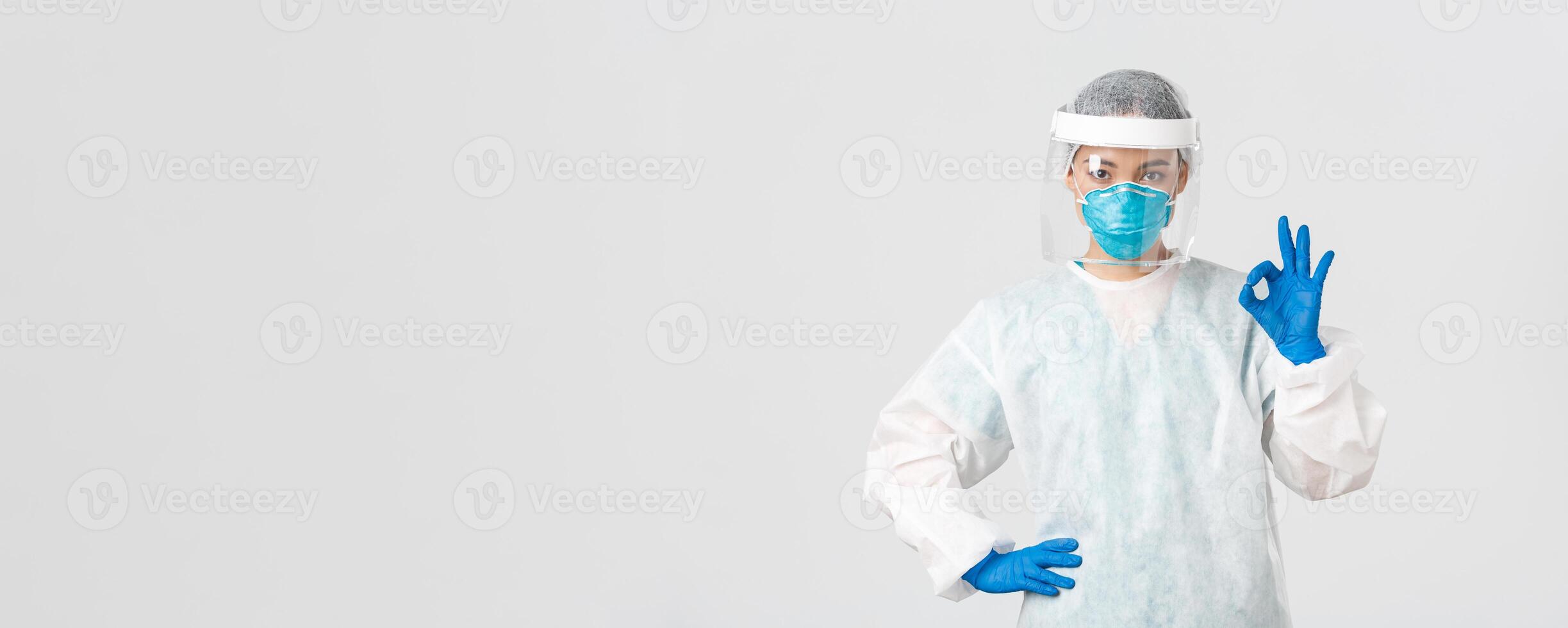 Covid-19, coronavirus disease, healthcare workers concept. Serious-looking professional female asian doctor in personal protective equipment, showing okay gesture, ensure safety of patient photo