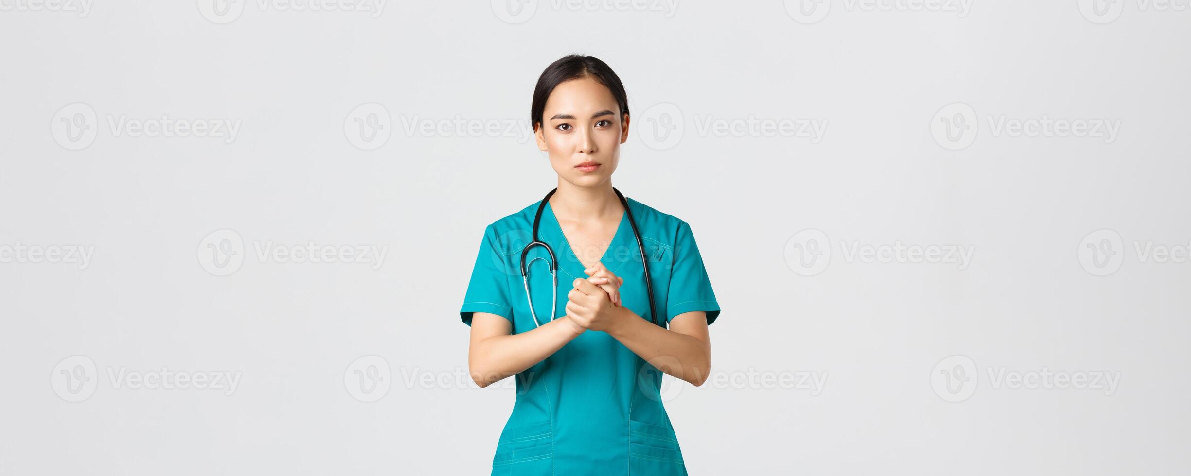 Covid-19, healthcare workers, pandemic concept. Hopeful serious-looking asian nurse, doctor asking something with concerned face, clench hands together in support during coronavirus, white background photo