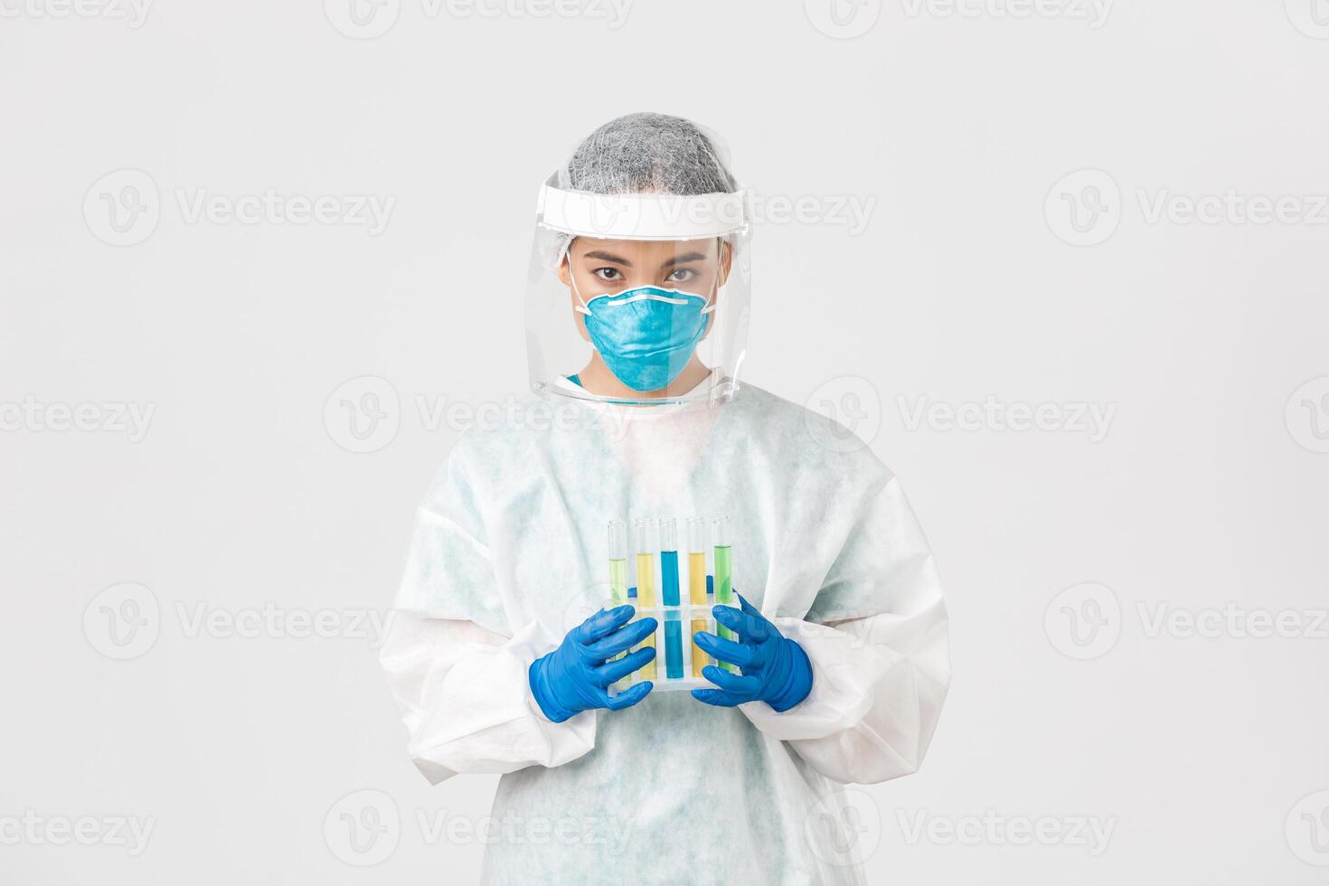 Covid-19, coronavirus disease, healthcare workers concept. Serious-looking careful asian female tech lab worker, researcher in personal protective equipment, holding test-tubes with vaccine photo