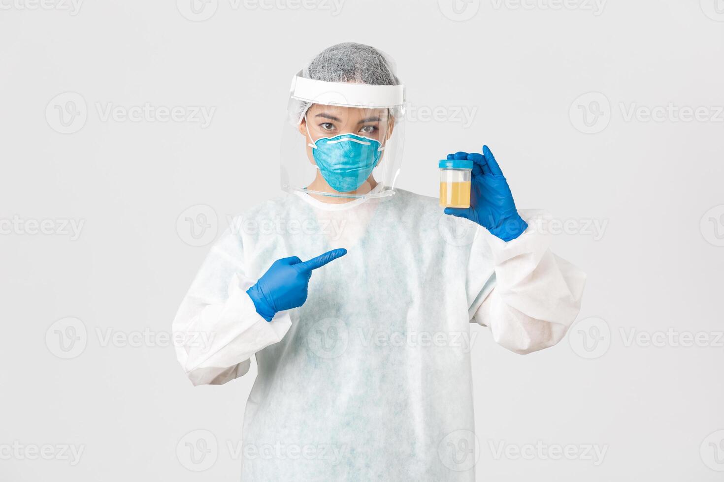 Covid-19, coronavirus disease, healthcare workers concept. Side view of serious-looking tech lab employee, researcher in personal protective equipment, pointing at urine analyze photo