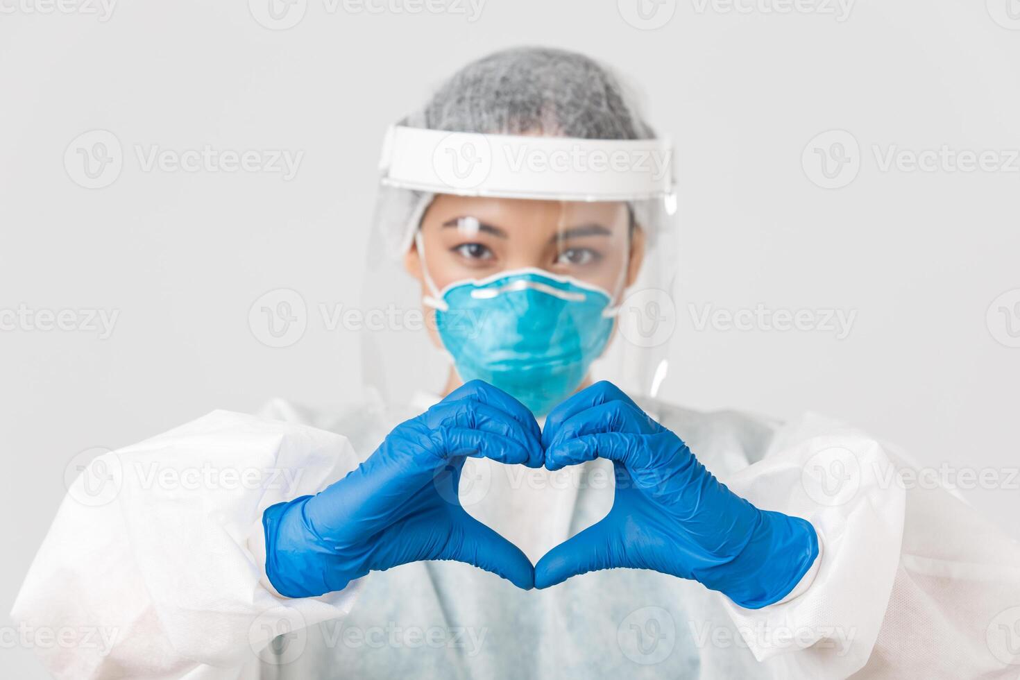 Covid-19, coronavirus disease, healthcare workers concept. Close-up of confident and caring asian female doctor in personal protective equipment, showing heart gesture to patients photo