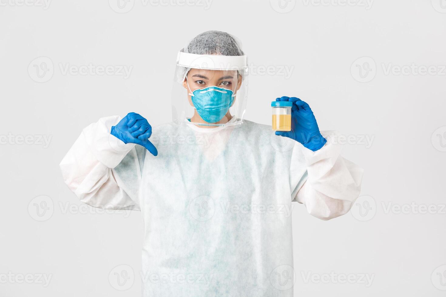 Covid-19, coronavirus disease, healthcare workers concept. Side view of serious tech lab employee, researcher in personal protective equipment show thumb-down in disapproval, bad analyze result photo