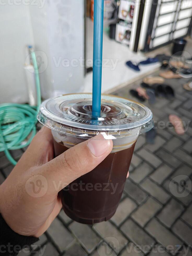 Hand putting a glass of iced black coffee. photo