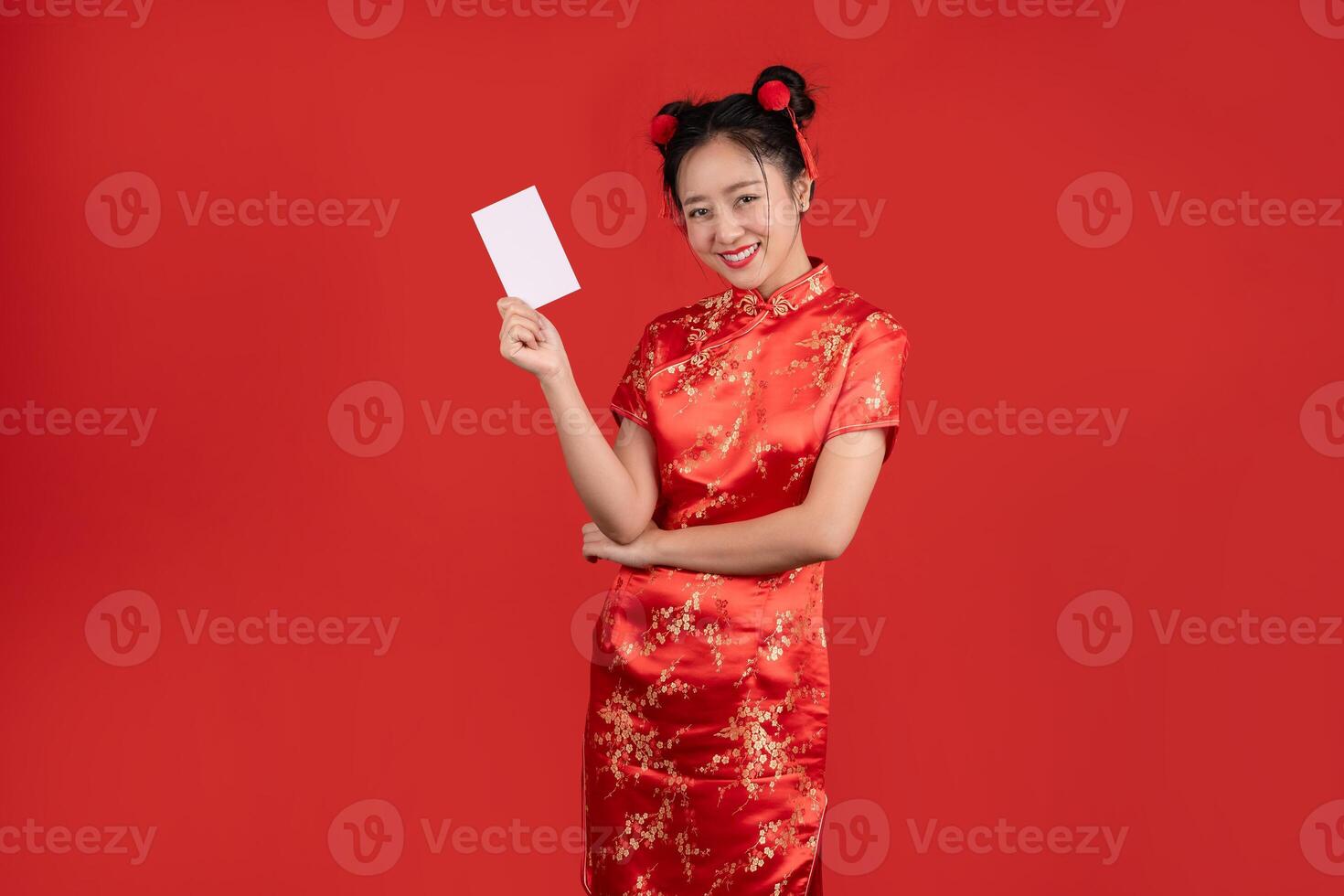 contento joven asiático mujer vistiendo rojo cheongsam participación crédito tarjeta aislado en rojo antecedentes. contento chino nuevo año foto