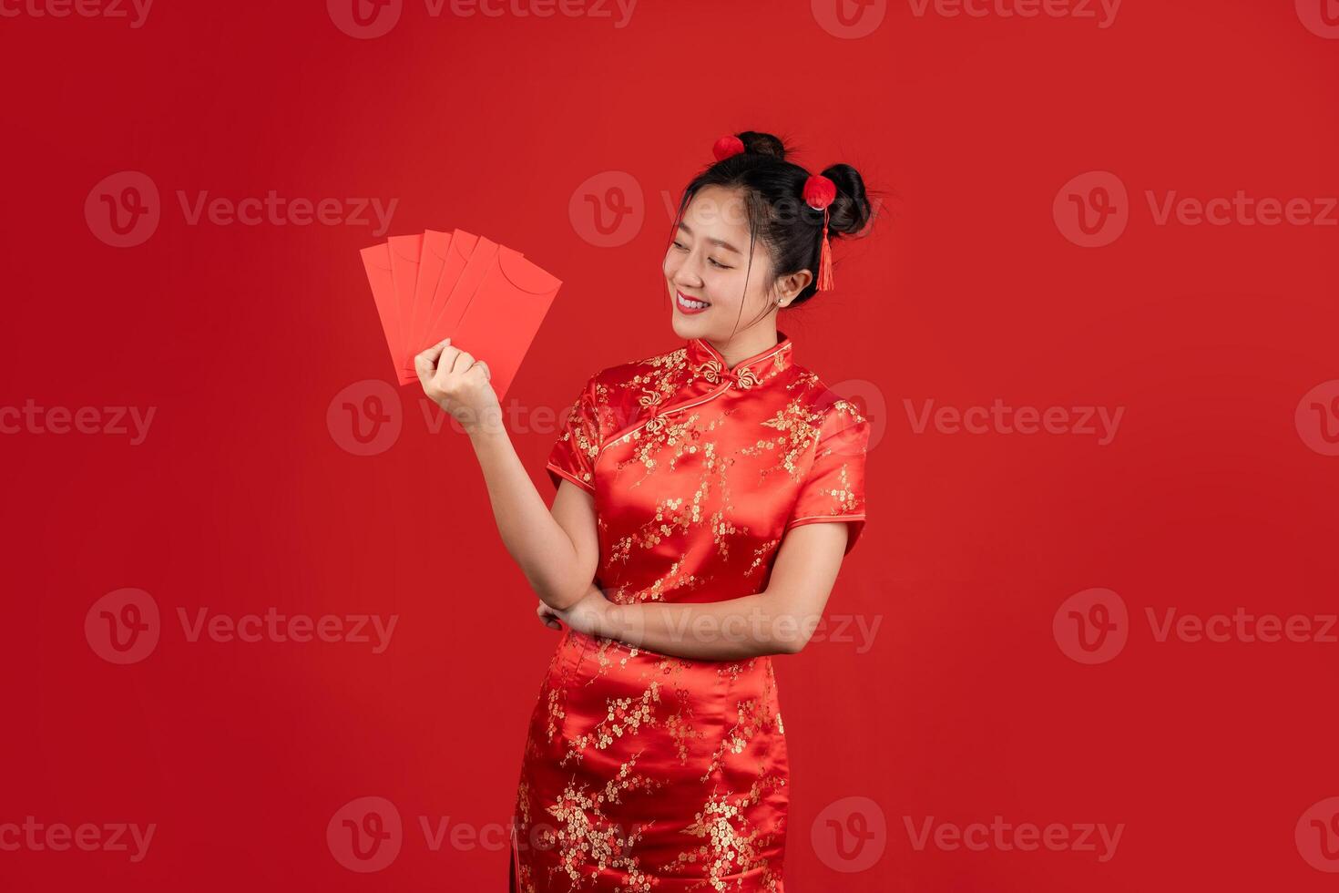 Asian woman wearing red cheongsam on red background. She is holding a red envelope. photo