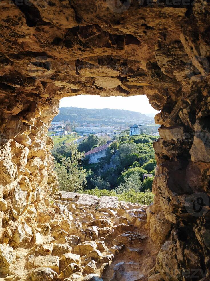View through the window of an ancient stone tower onto a natural landscape. photo