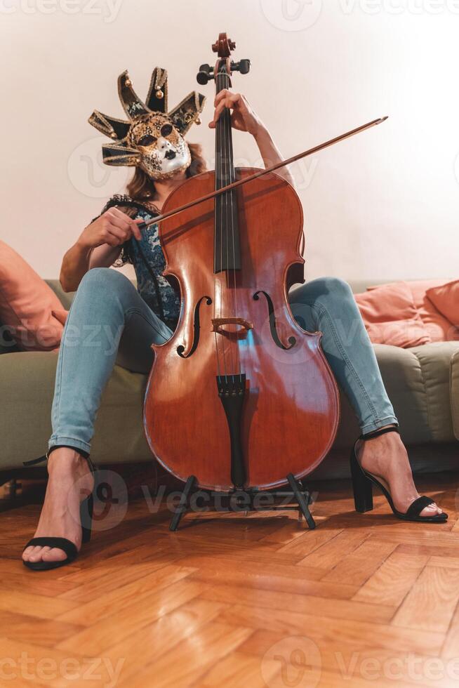 attractive woman wearing a mask is playing a cello photo