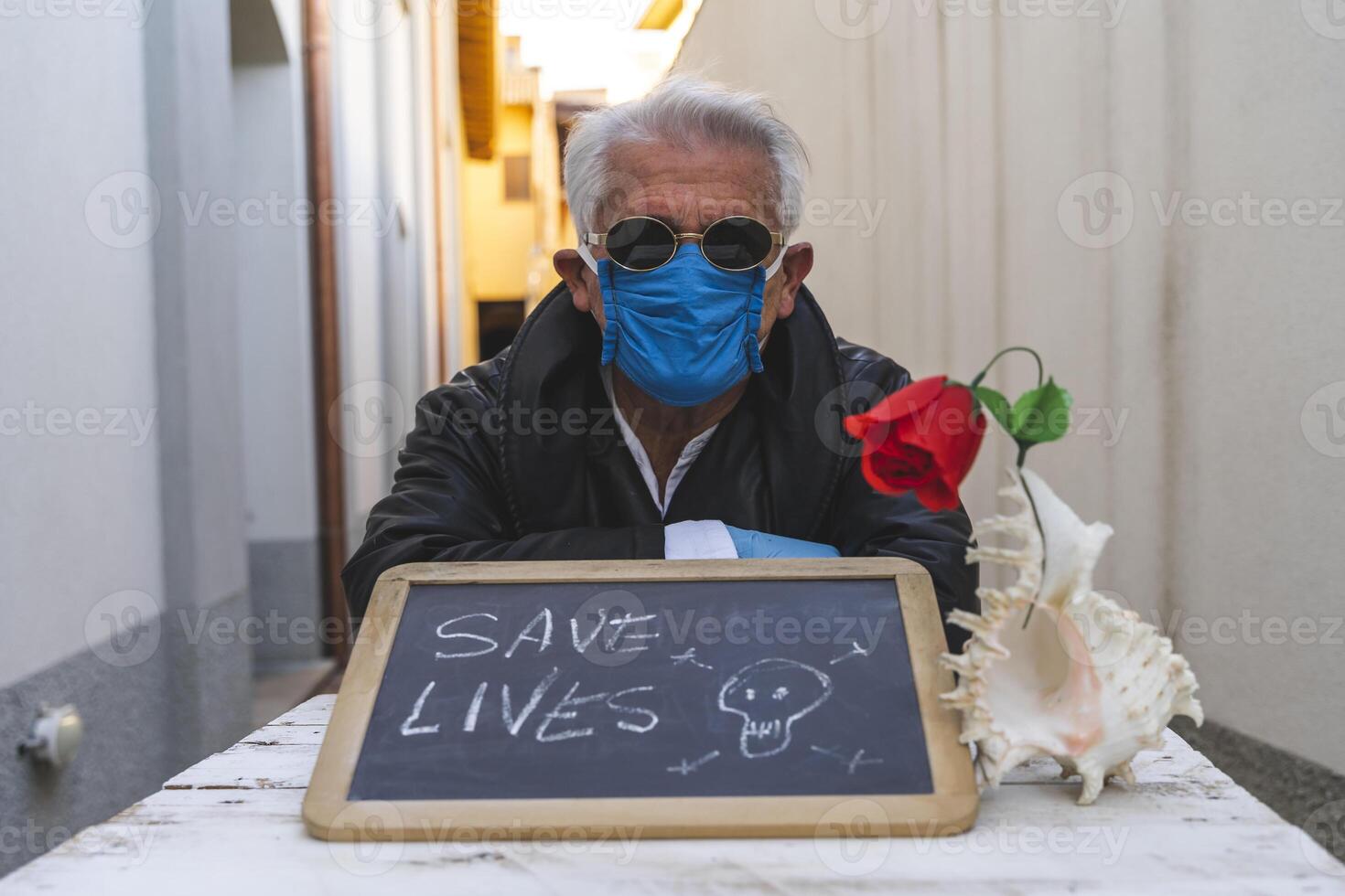 adult man with mask sitting at a table is showing a positive message photo