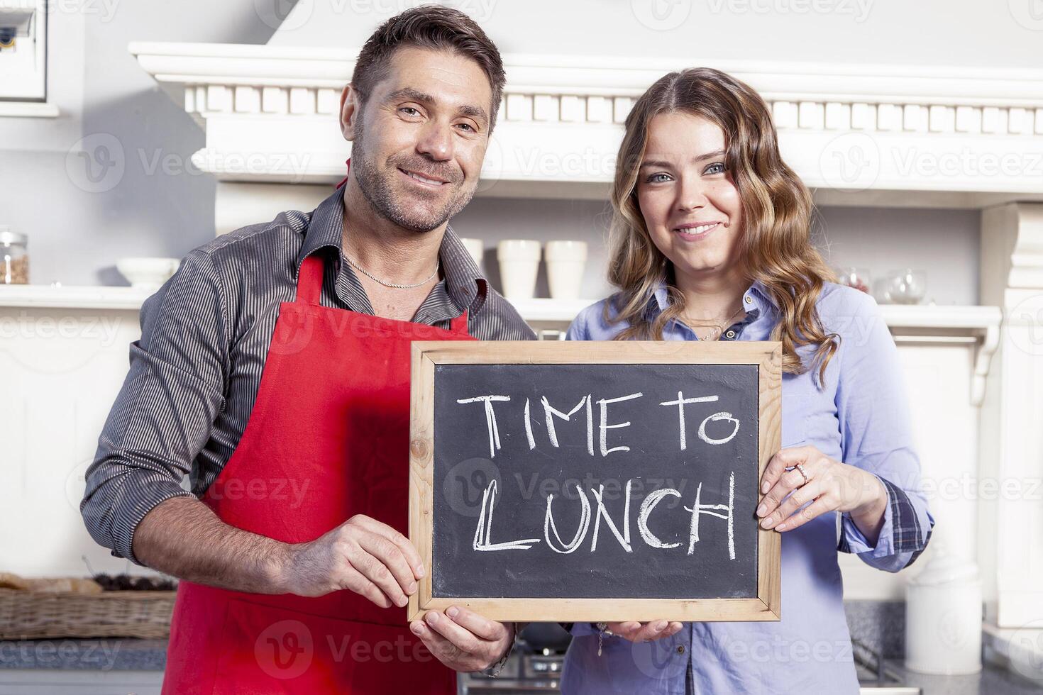 young couple shows a board with dinner invitation photo