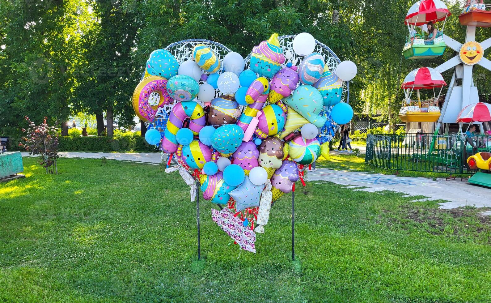 Heart-shaped design of helium balloons in a summer park. photo