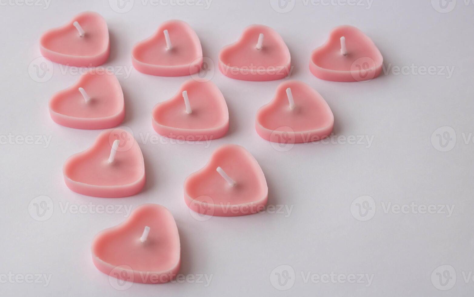 Small pink candles in the shape of a heart on a white background. A place for your text. photo