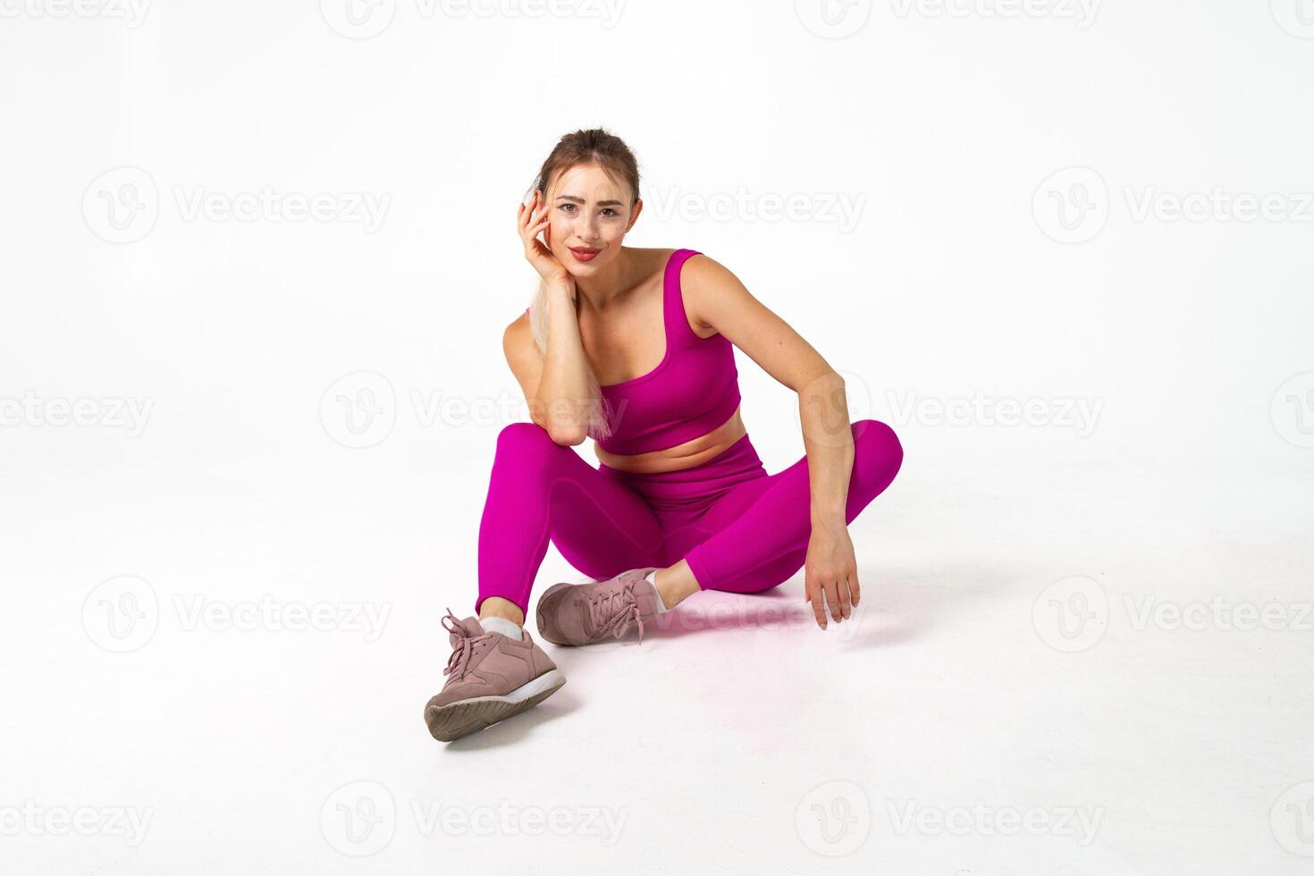 mujer en vibrante rosado Deportes atuendo sentado en piso con codo en rodilla y mano en contra cara foto
