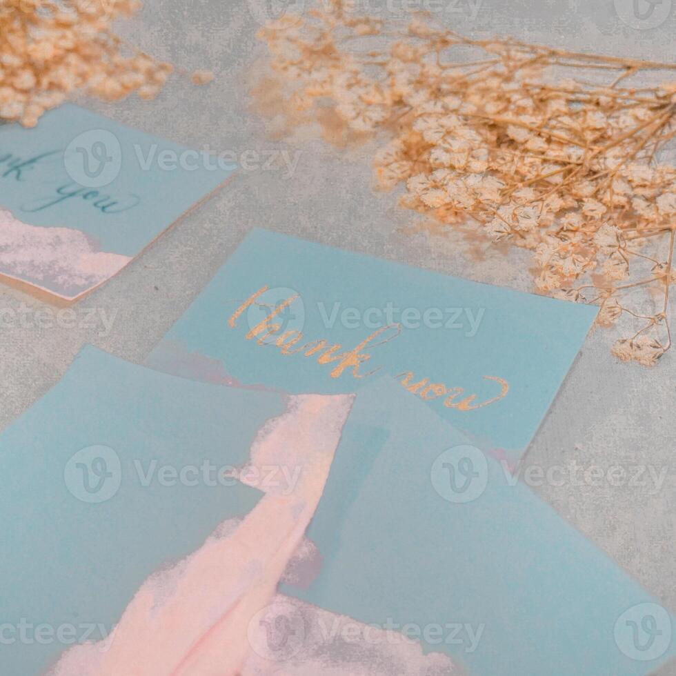 Boda invitación en el mesa con un ramo de flores de blanco rosas y un azul cinta. Boda invitación Bosquejo con seco flores en blanco de madera antecedentes foto