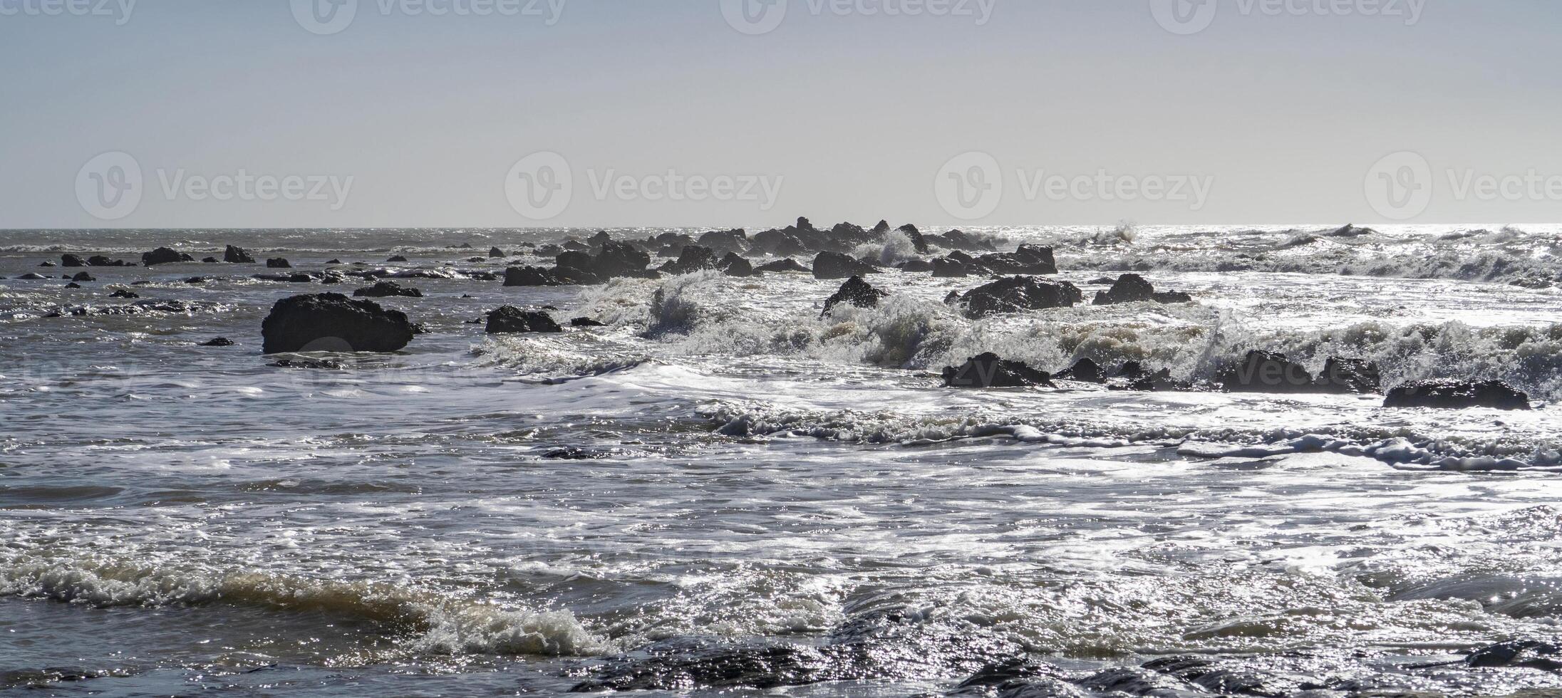 Blue sea and rocks storming. Wave spray over rocks. Rocky sea coast. photo