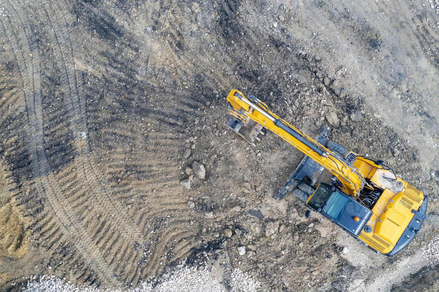 aéreo ver de el detenido amarillo excavador a un construcción sitio foto