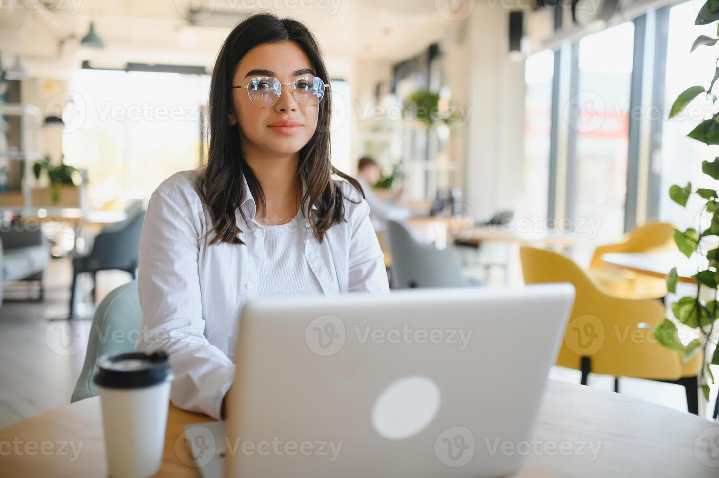 Joyful girl student studying online at cafe, using laptop and earphones, empty space photo