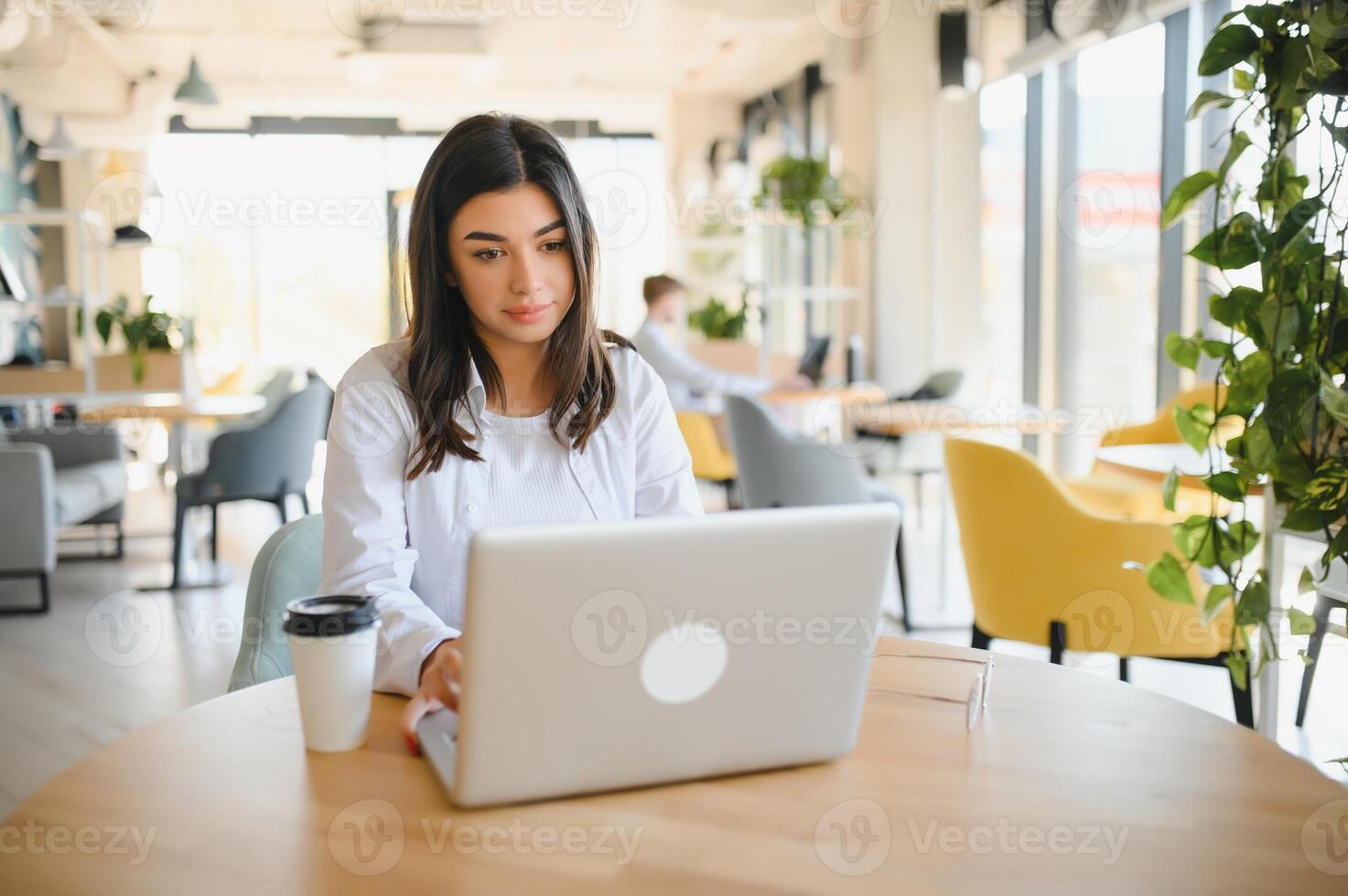 Joyful girl student studying online at cafe, using laptop and earphones, empty space photo