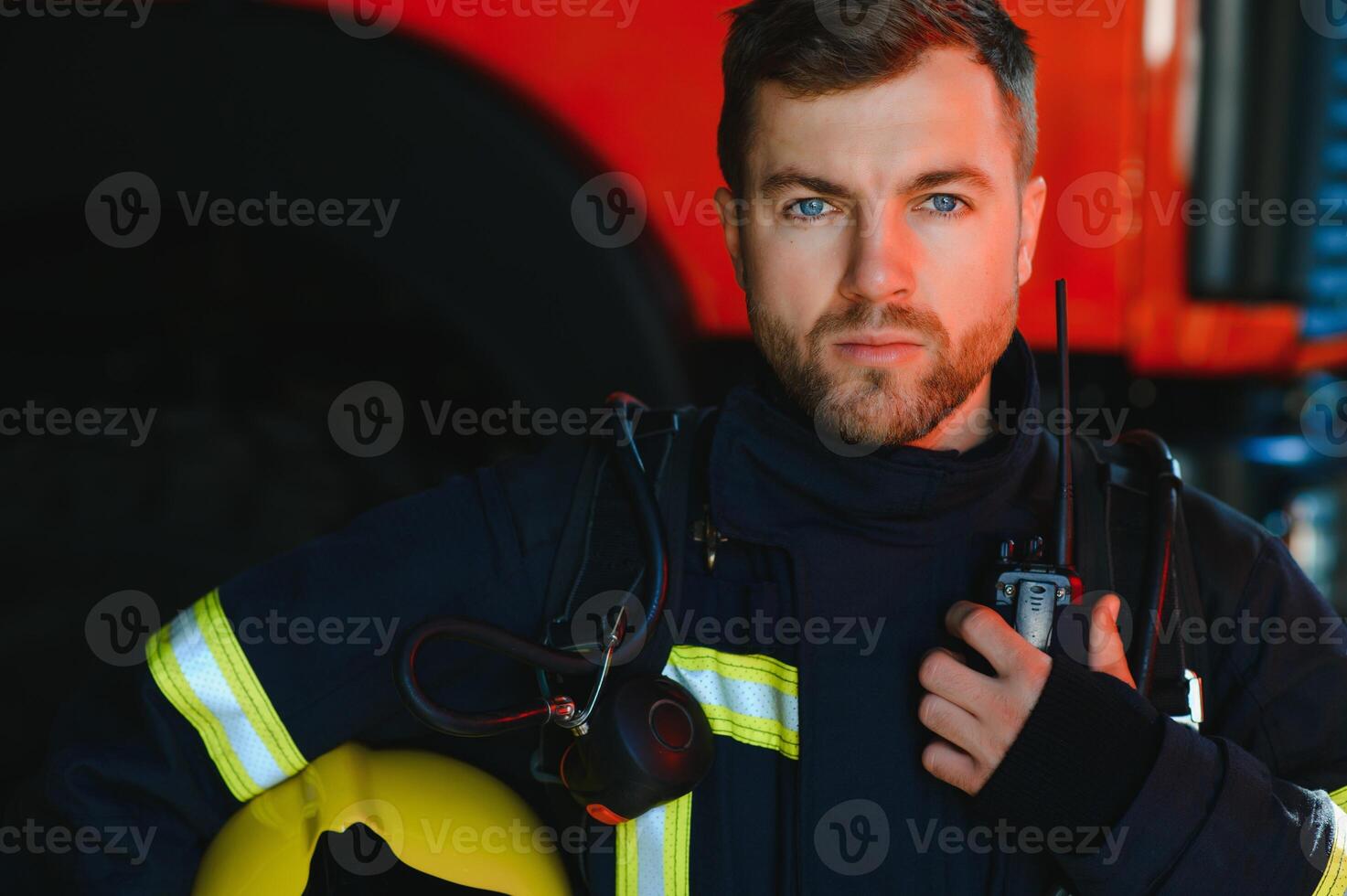 Firefighter portrait on duty. Photo fireman with gas mask and helmet near fire engine.