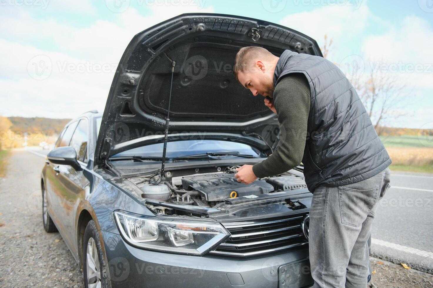 Handsome young man calling for assistance with his car broken down by the roadside photo