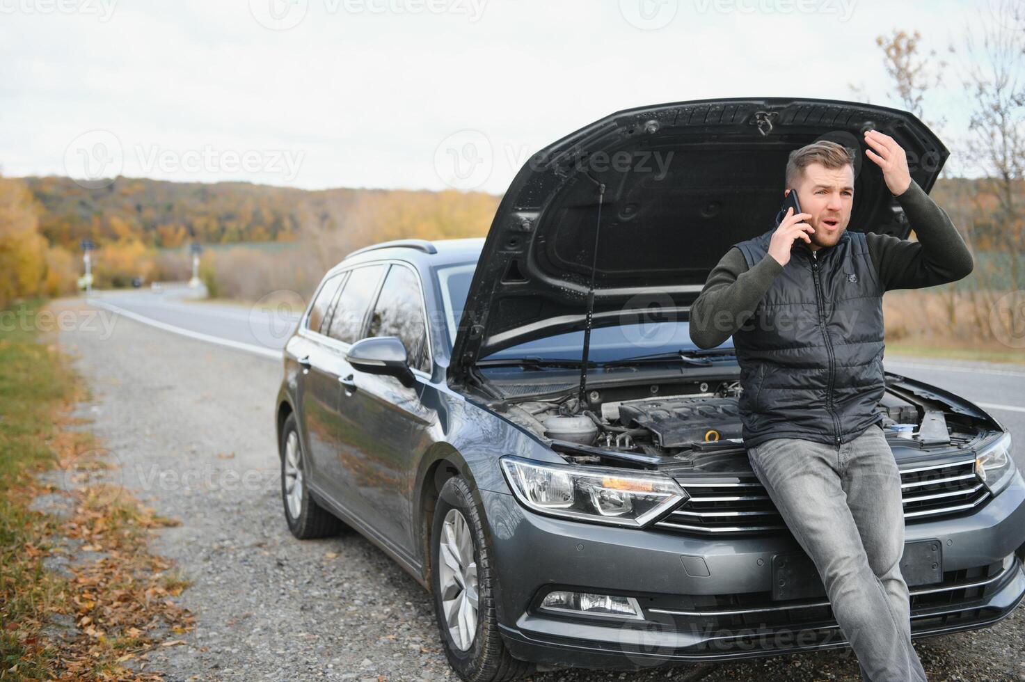 driver trying to figure out how to fix broken down car with red triangle to warn other road users photo