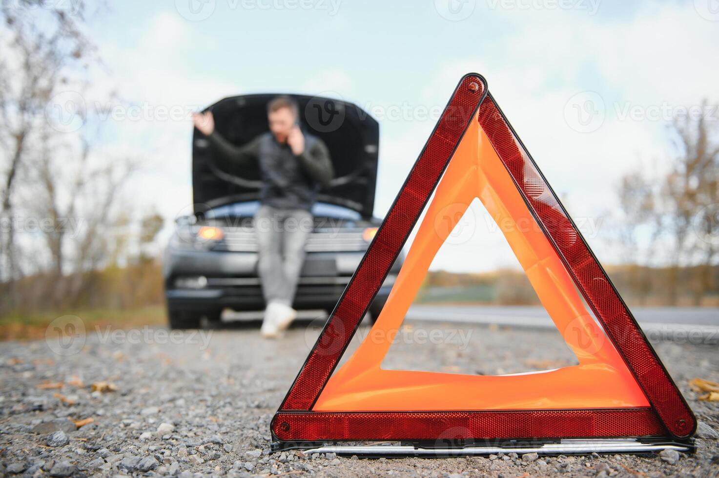 Handsome young man calling for assistance with his car broken down by the roadside photo