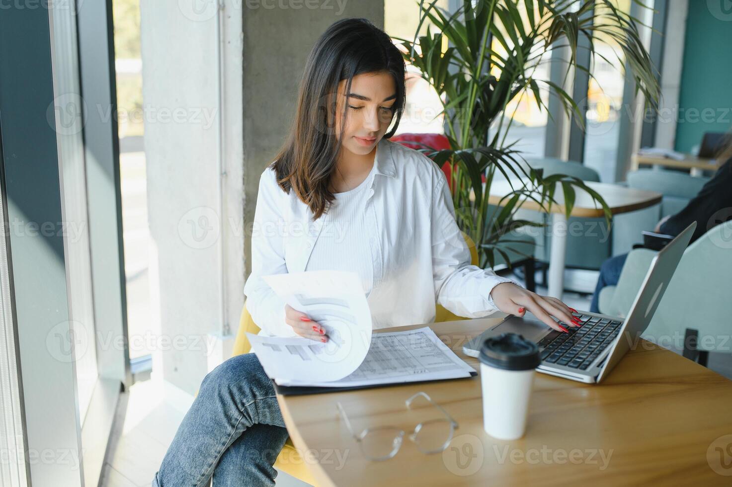 Joyful girl student studying online at cafe, using laptop and earphones, empty space photo