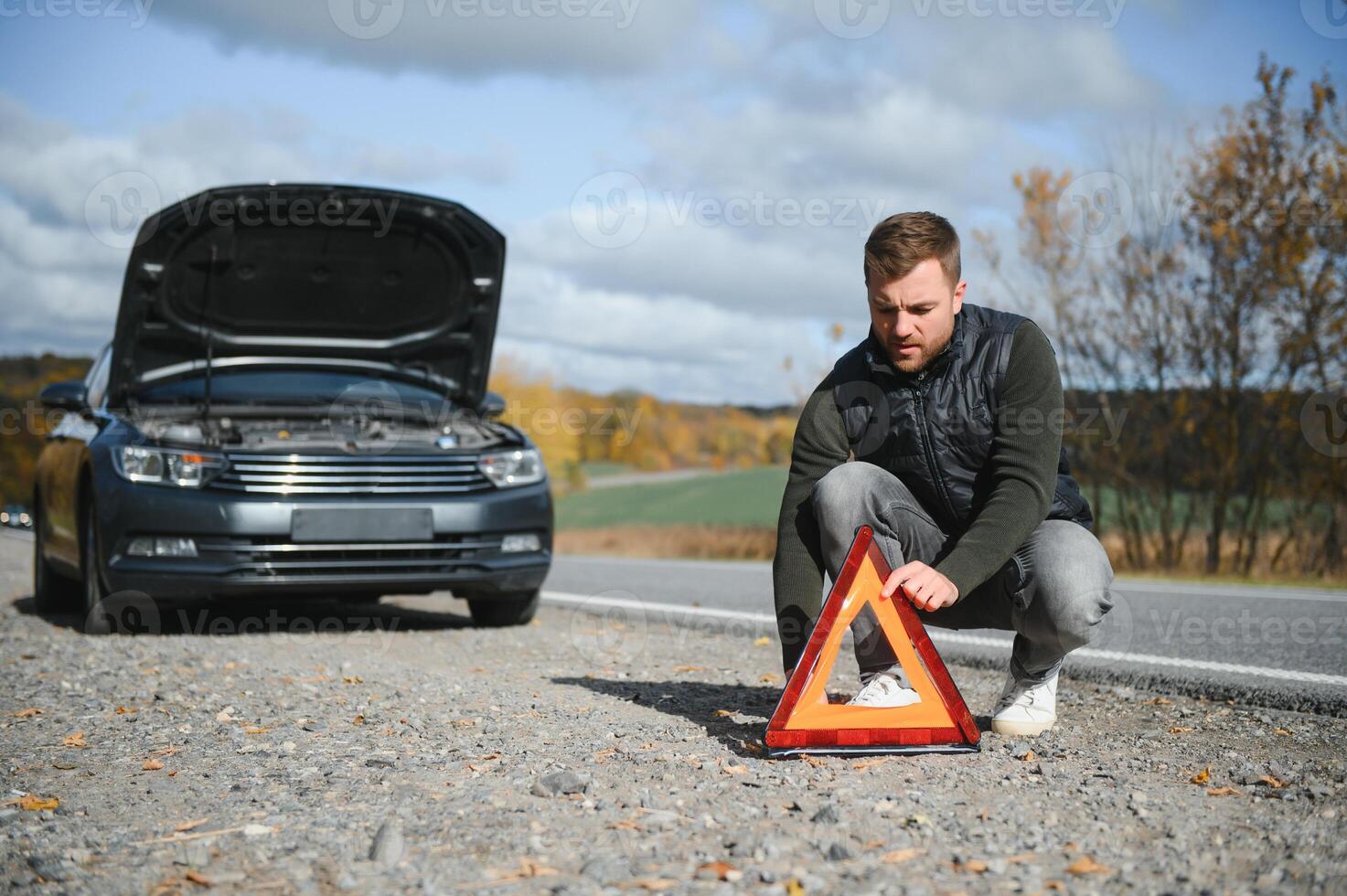 Handsome young man with his car broken down by the roadside photo