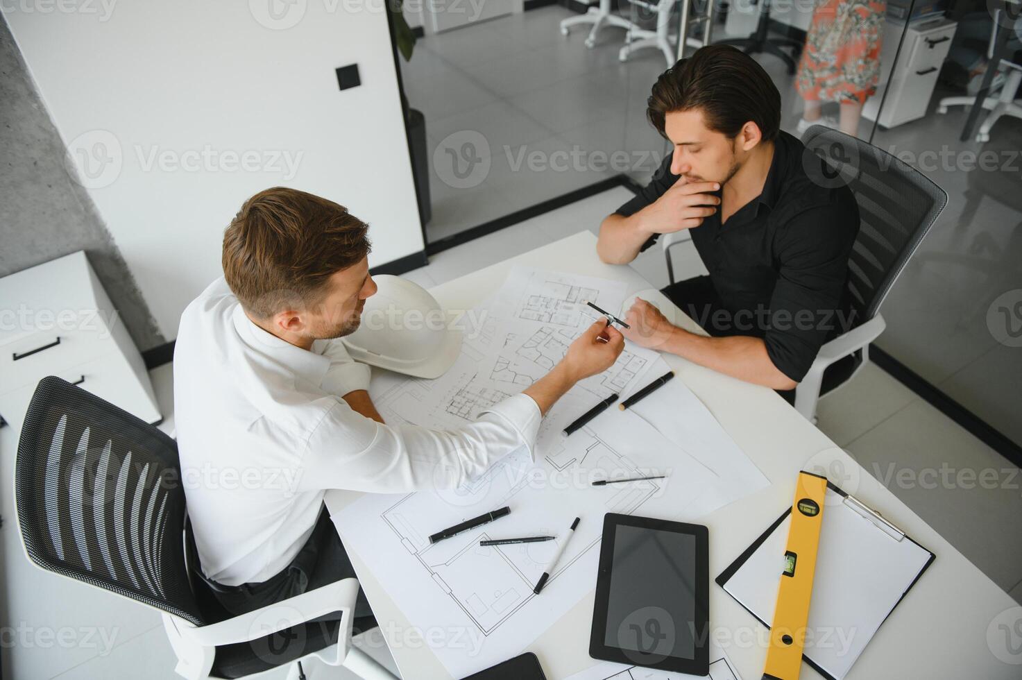 two people sit in front of construction plan and talk about the architecture photo