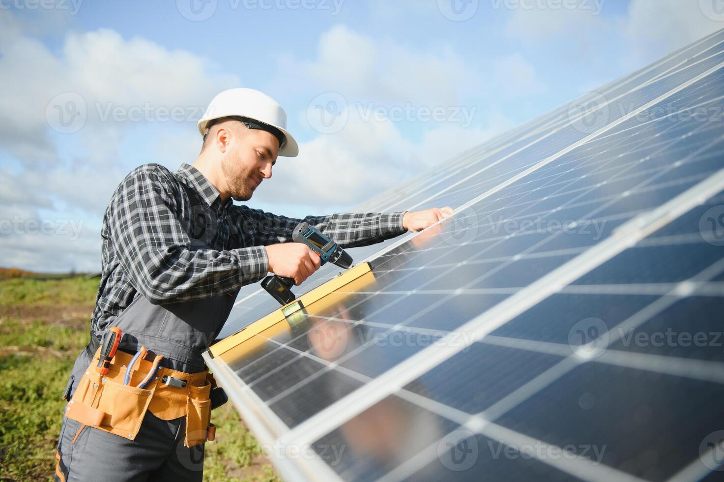 Male worker in uniform outdoors with solar batteries at sunny day. photo