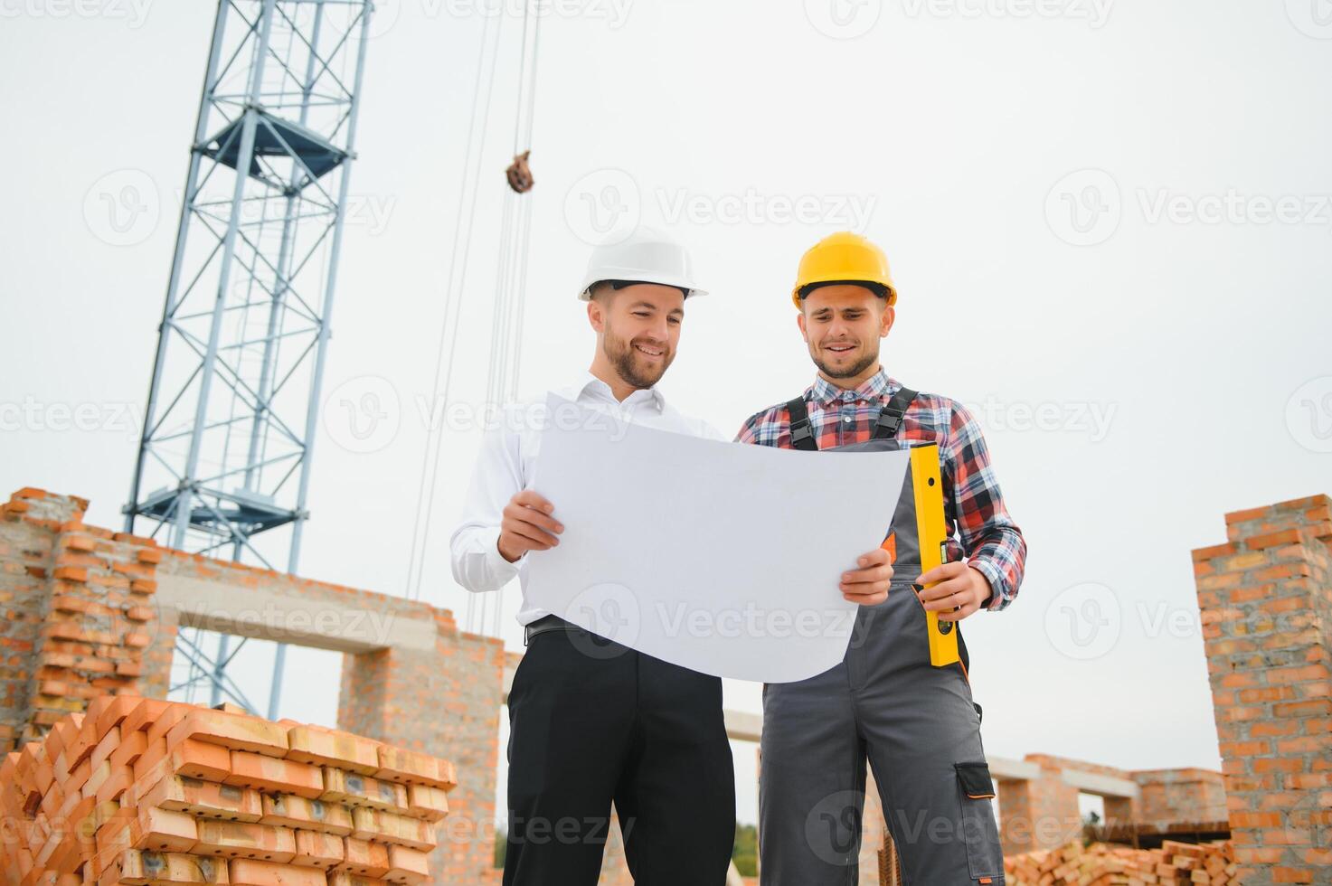 engineer and builder in hard hats discussing blueprint on construction site. photo