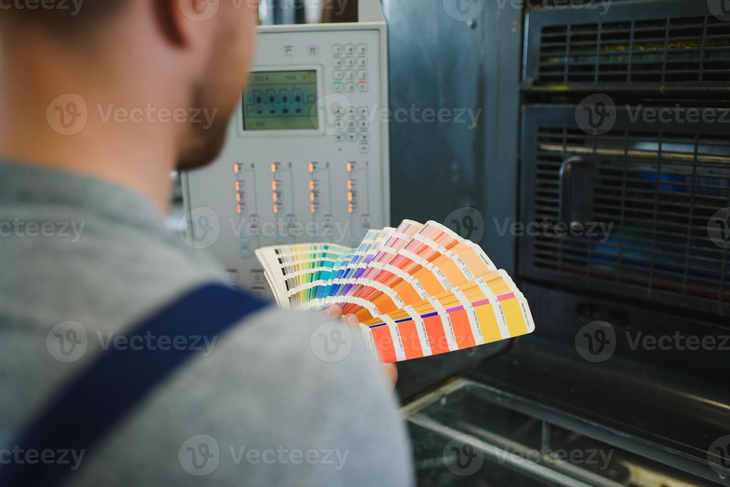 Man working in printing house with paper and paints photo