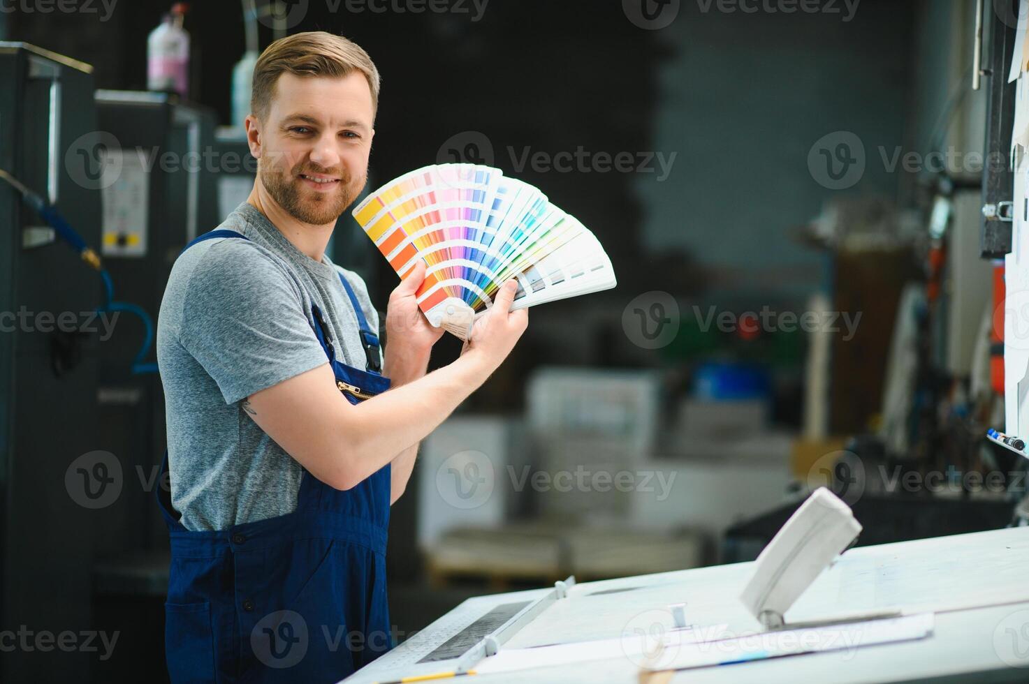 Man worker measuring printing color with spectrometer on the operating desk of the printing plant photo