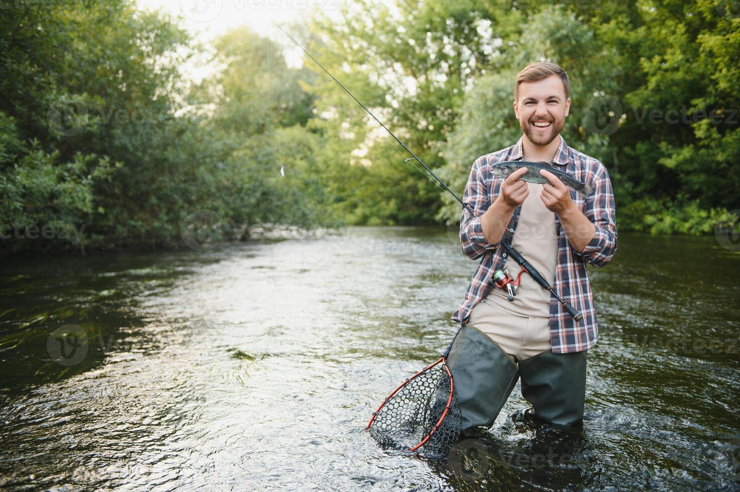 Fly-fisherman holding trout out of the water photo