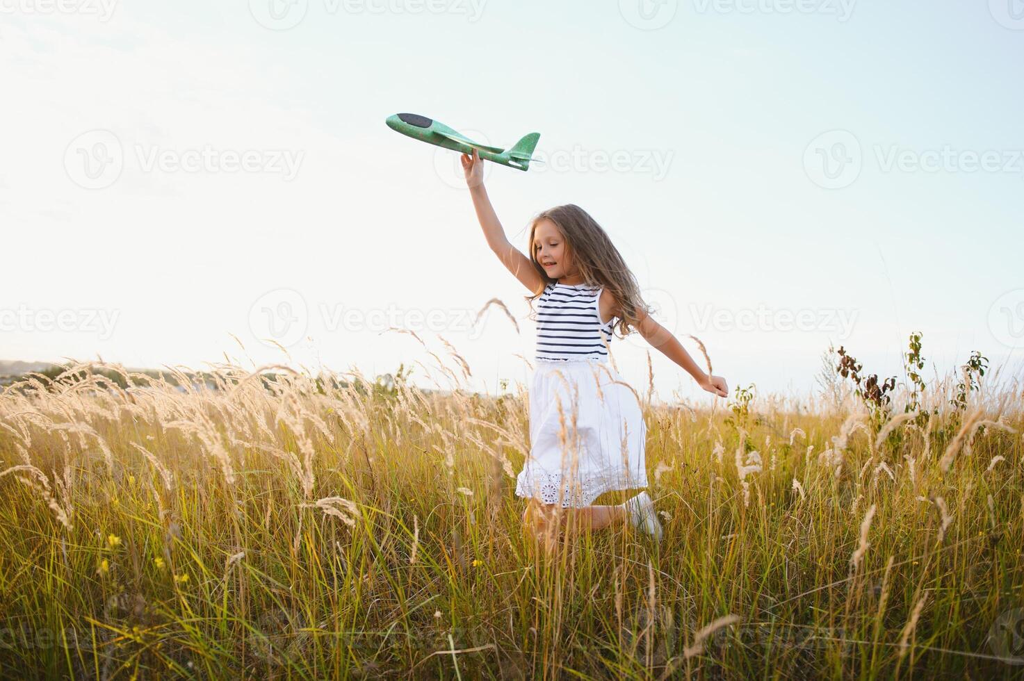 Happy girl runs with a toy airplane on a field in the sunset light. children play toy airplane. teenager dreams of flying and becoming a pilot. girl wants to become a pilot and astronaut. Slow motion. photo