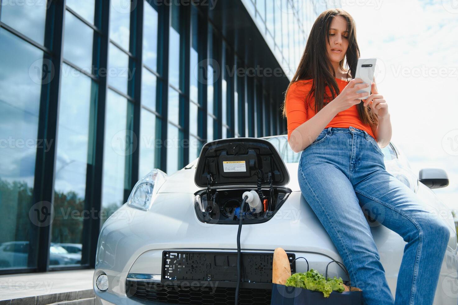 Woman charging electro car at the electric gas station photo